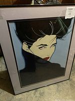 Frontal photo of the framed Patrick Nagel print depicting a woman with black hair and a high collar against a muted background.