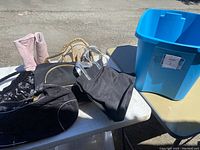 View of purses, shoes and storage bin laid on table outdoors.