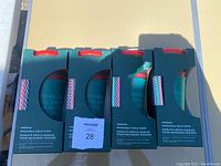 Four boxed Starbucks reusable cold cups with holiday design, red lids and striped straws visible inside the packaging.