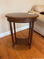 Side angle showing oval tabletop with detailed carved edge and turned legs.