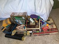 Photo showing the full lot of assorted games, ping pong paddles, and outdoor first aid kits arranged on carpeted floor.