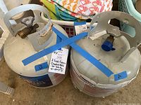 Photo showing both propane cylinders side by side with identifying blue tape labels A and B and a note describing the contents: A - 3/4 full, B - empty.