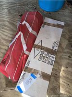 Sealed white box labeled 'Imperial Mini Golf' next to croquet bag.