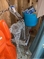 Full view of white woven plastic reindeer attached to sled with prewired string lights. Blue bucket on sled with boxed LED lights.