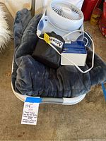 Laundry basket containing soft grey plush throw blanket, Onwego travel kit, and Honeywell fan from top view