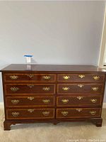 Front view of entire dresser showing eight drawers with brass fittings and herringbone inlay on drawer fronts.