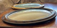 Two antique oval bubble glass frames shown side by side on a wooden table.