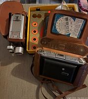 Kodak folding camera in leather case, video camera, flash and exposure guide visible
