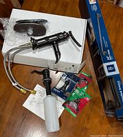 Photo showing the faucet components, soap dispenser, towel rack box, and small hardware packages.