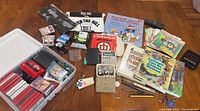 Photo showing organized collection of cassette tapes, children's books, and other printed media arranged on the floor.