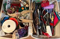 Two large storage bins filled with a variety of gift bags in different patterns and sizes, plus ribbons and bows scattered throughout.