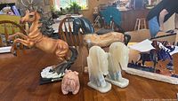 View showing multiple horse statues including a large rearing horse figurine, black horse sculpture, chess piece bookends shaped as horse heads, and small bulldog figurine.