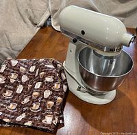 Mixer with bowl and fabric cover on wooden surface
