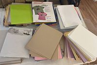Overview of various stacks of colored cardstock, DIY transfers, and printer paper