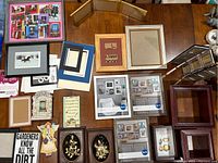 Photo of assorted picture frames on a wooden table including boxed frames and various styles - wooden, black, colorful, ornate
