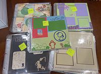 Overview of various premade scrapbooking layouts in plastic sleeves with post-it labels indicating themes such as 'Family,' 'Pets,' and 'Vintage.'