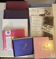 Multiple Creative Memories 12x12 Scrapbook albums in various colors including maroon, purple, white, and pink; unopened packages of scrapbook pages and page protectors