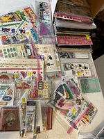 Wide view of assorted scrapbooking papers and various small sticker packs spread on a table, showing colors and themes of items
