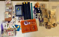 Photo showing scrapbooking and crafting tools including cutters, rulers, punches, adhesives, and wooden rubber stamps.