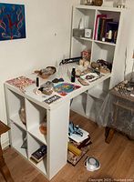 White hobby desk with cubby storage hutch, some shelves have decorative items placed on them.