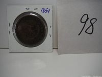 Front side of 1854 Bank of Upper Canada one penny token showing crossed keys and sword under a crown, encased in holder.