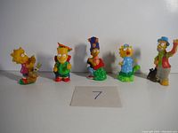 Set of five small Simpsons character figurines on white background with label showing number 7.