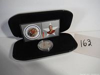 Photo of entire set in black display box with stamps and coin visible