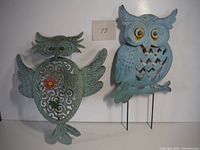 Photo showing both metal owl garden decorations side by side, highlighting their shapes and colors.