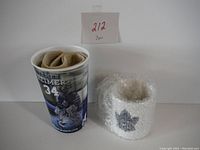 Photo showing a plastic James Reimer cup and a bubble wrapped ceramic mug with Maple Leafs logo