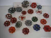 Top-down view showing all 19 metal valve handles arranged closely together on a white surface.