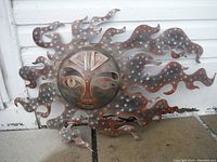 Full view of the large metal sun wall art showing the face and flame-like outer rays with white dots.