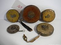 Full set of six measuring tapes arranged on white background, showing their overall condition and variety in casing materials.