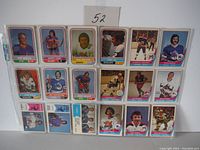 Photo showing 18 mid 1970s WHA hockey cards arranged in 3 rows of 6, featuring players from various teams including Howe, Marty, Mark with some card wear visible