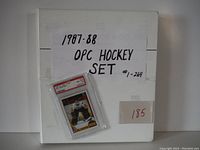 Binder containing the 1987-88 OPC hockey card set with a paper label #1-264 and a Bill Ranford graded card taped on the front