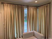 Corner view of two drapery sets hung on adjoining windows, showing full drop and rod alignment