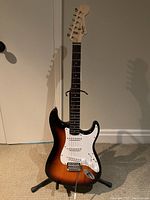 Full-length front view of sunburst Stratocaster on stand