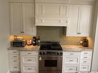 Overview of entire cabinet run including hood cover, base and wall cabinets either side of stove
