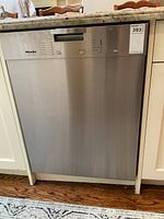 Frontal view of built-in stainless steel dishwasher under countertop