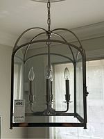 Frontal view of chandelier showing candle-style bulbs inside clear glass and chrome frame