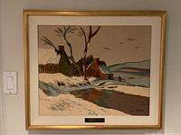 Framed needlepoint art full view showing snowy cottages and water
