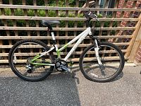 Right side profile showing white and green frame, wheels, suspension fork, drivetrain