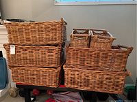 Front view of stacked wicker baskets showing variety of sizes and wood handles