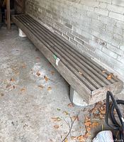 Angled view of the wooden bench top against brick wall showing overall length and wear