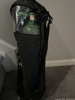 Photo of oxygen carry on kit featuring black soft carrying case with visible green oxygen tank and attached green oxygen mask inside.