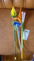 Overview of the four art glass flower stems in various colors including yellow, orange, blue, and clear-blue on brown leather background.