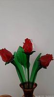 Three red crystal flowers held in green crystal leaves in a vase (vase not included in lot)
