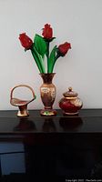 Three Egermann Czech Bohemian glass items displayed side by side: vase with red rose glass stems, covered dish, and basket-style dish with handle, all with gold plating and floral decoration.