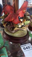 Close-up front view of red cardinal figurine on branch with two eggs on wood base.