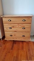 Front view of the three drawer pine dresser showing metal cup handles and wood grain.