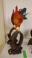 Two rooster figurines standing on rusted horseshoe bases, detailed feather texture and colorful paint